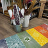 A vibrant cotton yoga rug with 7 chakras design in orange yellow green blue and red geometric mandala patterns