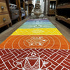 A vibrant cotton yoga rug with rainbow chakra colors and white geometric patterns on each band