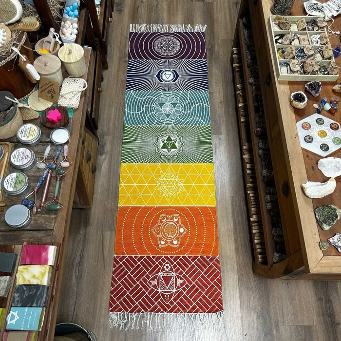 A vibrant cotton yoga rug with seven chakra colors woven geometric patterns and fringe detailing