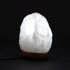 A glowing white crystal rock himalayan salt lamp with rough texture showing its natural hygroscopic properties