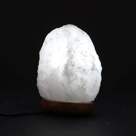A glowing white crystal rock himalayan salt lamp with rough texture showing its natural hygroscopic properties