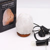 A white crystal rock himalayan salt lamp with rough texture and polished wooden base showing hygroscopic properties