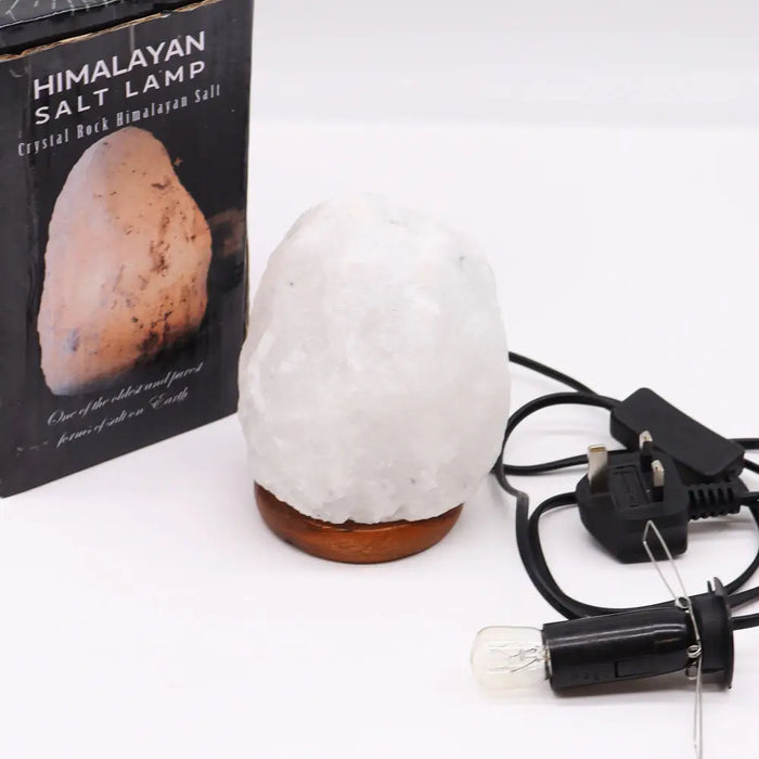 A white crystal rock himalayan salt lamp with rough texture and polished wooden base showing hygroscopic properties