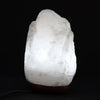 A glowing white himalayan salt lamp with a rough texture and warm light weighing 2 to 3 kilograms