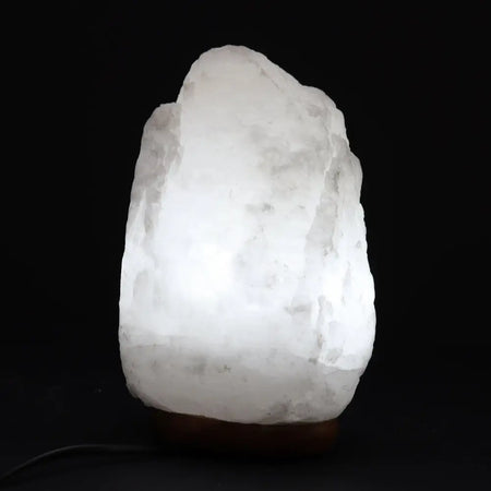 A glowing white himalayan salt lamp with a rough texture and warm light weighing 2 to 3 kilograms