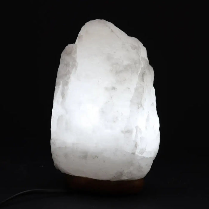 A glowing white himalayan salt lamp with a rough texture and warm light weighing 2 to 3 kilograms