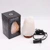 A white himalayan salt lamp with an irregular crystal rock shape on a brown ceramic base weighing 2-3kg