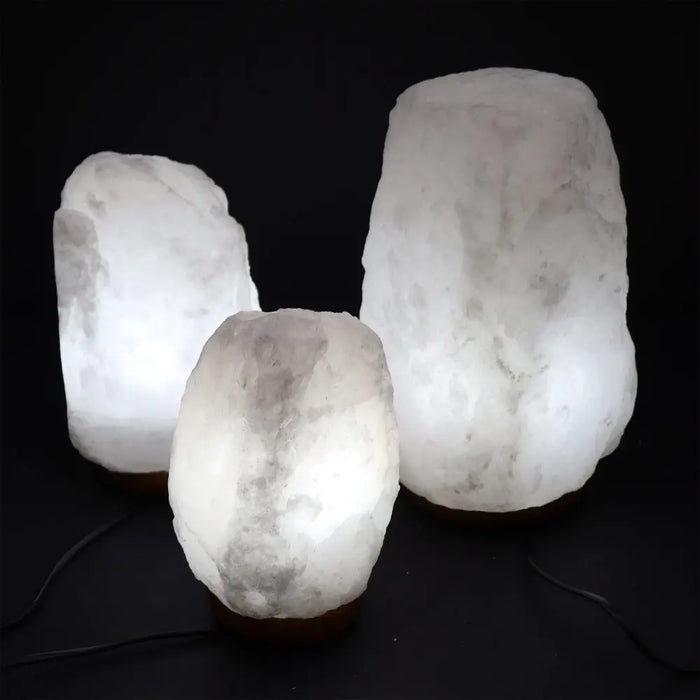 Three illuminated himalayan salt lamps in natural irregular shapes with translucent white to pale gray salt lamp crystals