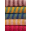 Stack of colorful striped throw fabric bolts in green and blue made from recycled cotton for cozy home use