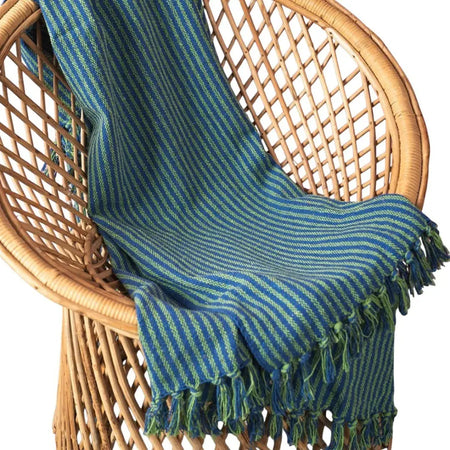 A cozy blue and green striped throw made of recycled cotton with fringed edges for casual home use