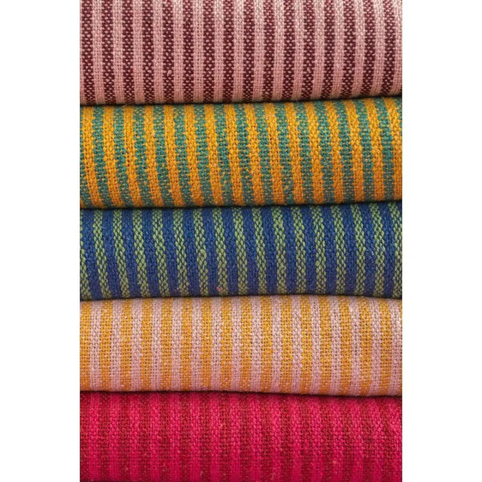 Stacked striped throws in recycled cotton with pale pink mustard and vibrant earthy tones and bold hues