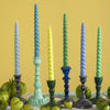 A set of six twisted dinner candles in pastel blue green and yellow on glossy ceramic candlesticks from daisy snow coast