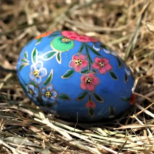 A vibrant blue dalit goods kashmiri style solid egg with pink white floral patterns outlined in gold