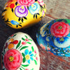 Vibrantly painted wooden nesting eggs in dalit goods kashmiri style with intricate floral designs in yellow blue and white