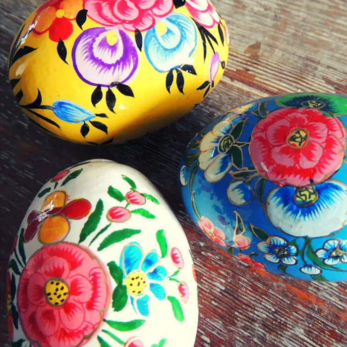 Vibrantly painted wooden nesting eggs in dalit goods kashmiri style with intricate floral designs in yellow blue and white