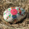 A hand-painted dalit goods kashmiri style solid egg with pink blue purple and orange floral designs on white surface
