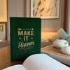 Dark green velvet notebook with gold foil lettering that reads make it happen and a decorative arrow above the text
