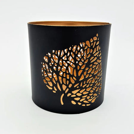 Black metal votive candle holder with gold leaf design etched on its side for decorative use