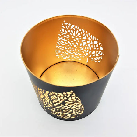 Black and gold metal votive candle holder with intricate leaf die-cut patterns for decorative use