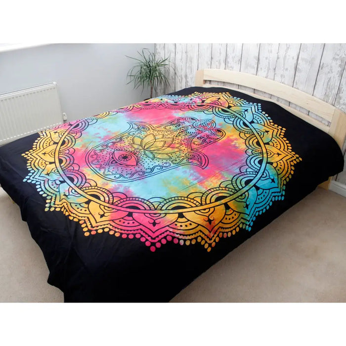 Double cotton bedspread with vibrant rainbow tie-dye and black hamsa mandala design used as wall hanging on bed