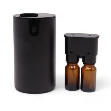 Black cylindrical essential oil waterless nebulizer with two amber glass bottles and a usb charging light at the base
