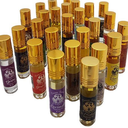 A collection of clear glass dream spirit perfume oil rollerball bottles with gold caps and colorful scent labels