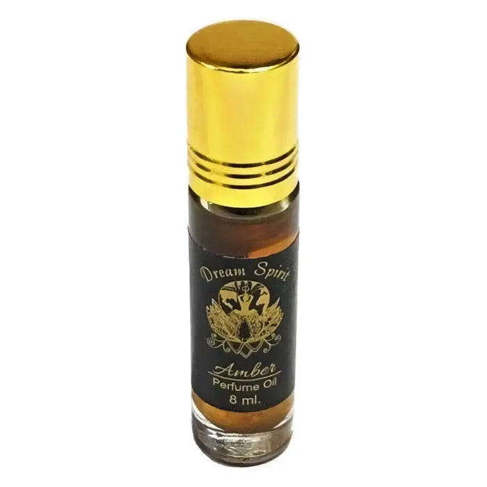 A sleek 8 ml amber glass rollerball bottle of dream spirit perfume oil with a golden cap and black label with gold lettering