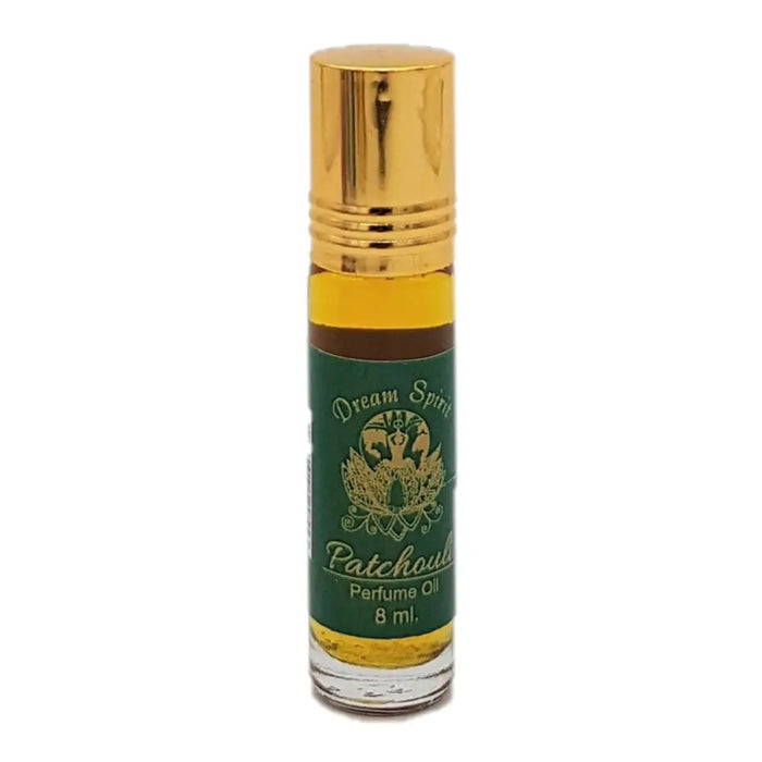 A small clear glass bottle of dream spirit perfume oil with a gold rollerball cap and green label with gold lettering