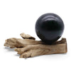 A driftglow lamp with an emerald crackle shade and a smooth black stone on a natural driftwood base