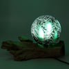 A driftglow lamp with an emerald crackle shade glowing green on a rustic wooden base