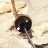 Black cylindrical cable with embossed text inserted into rustic wood near driftglow lamp grey luna shade opening