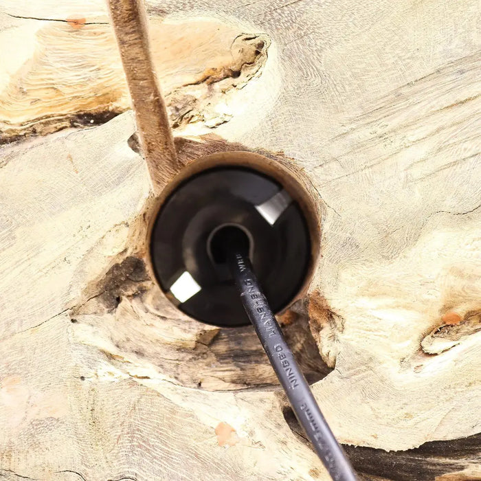 Black cylindrical cable with embossed text inserted into rustic wood near driftglow lamp grey luna shade opening