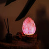 A purple crackle driftglow lamp with a glowing pink egg-shaped salt lamp and textured crackle lotus flower surface