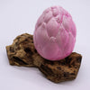 A pink cracked surface dinosaur egg sculpture with a matte finish on driftwood driftglow lamp purple crackle lotus flower shade