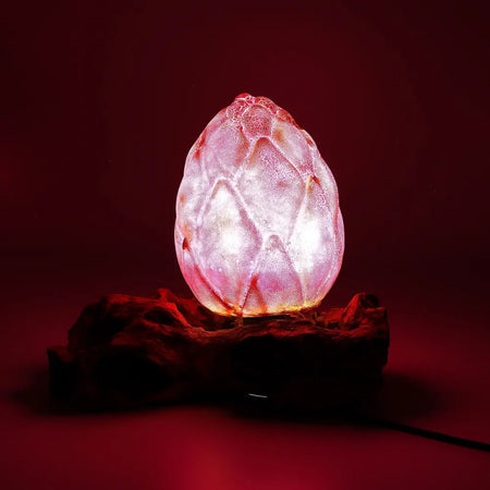 A translucent egg-shaped driftglow lamp with a purple crackle lotus flower shade glows softly in warm pink and white hues
