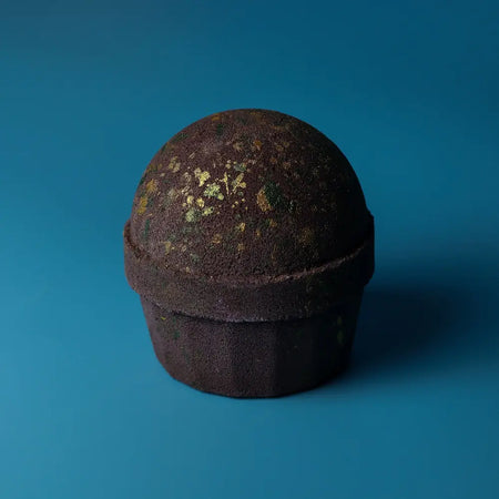 Dark brown bath bomb with textured speckled surface and gold flecks named dubai bath bomb emerald oudh truffle