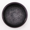 Black ceramic earth powder singing bowl with intricate raised patterns featuring five buddha symmetrical design inside