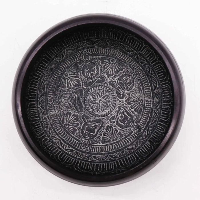 Black ceramic earth powder singing bowl with intricate raised patterns featuring five buddha symmetrical design inside