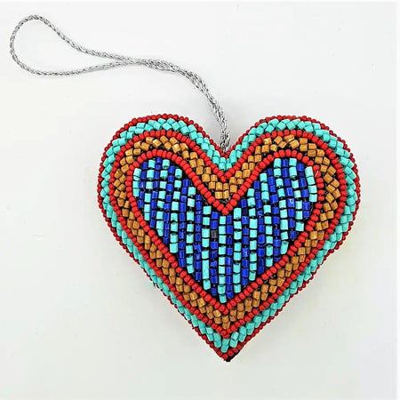 A beaded heart-shaped hanging ornament in turquoise red and blue with a silver cord from five designs collection