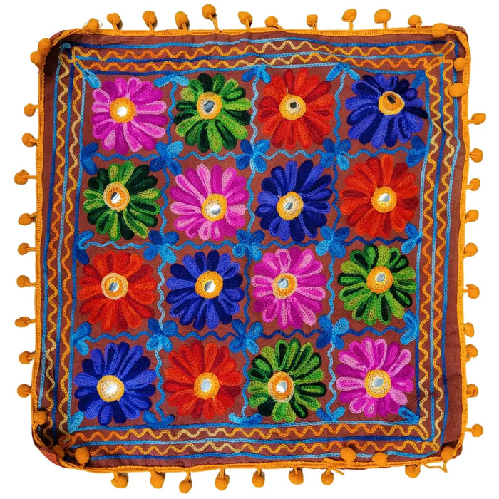 Vibrant embroidered cushion cover with colorful floral patterns in pink green red and blue with orange pom-pom braiding