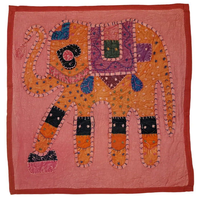A vibrant indian patchwork cushion cover with an embroidered orange and purple elephant on a pink standard cushion