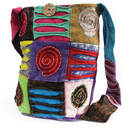 A colorful ethnic sling bag with patchwork fabric and embroidered spiral patterns in purple red blue green and yellow