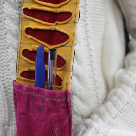 Ethnic sling bag with vibrant yellow and red fabric pen holder and pink denim pocket with stitched cut-out slots