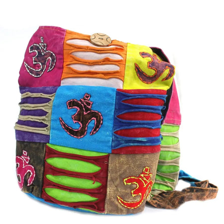 A teal ethnic sling bag with vibrant patchwork fabric squares and embroidered om symbols in stitched patterns
