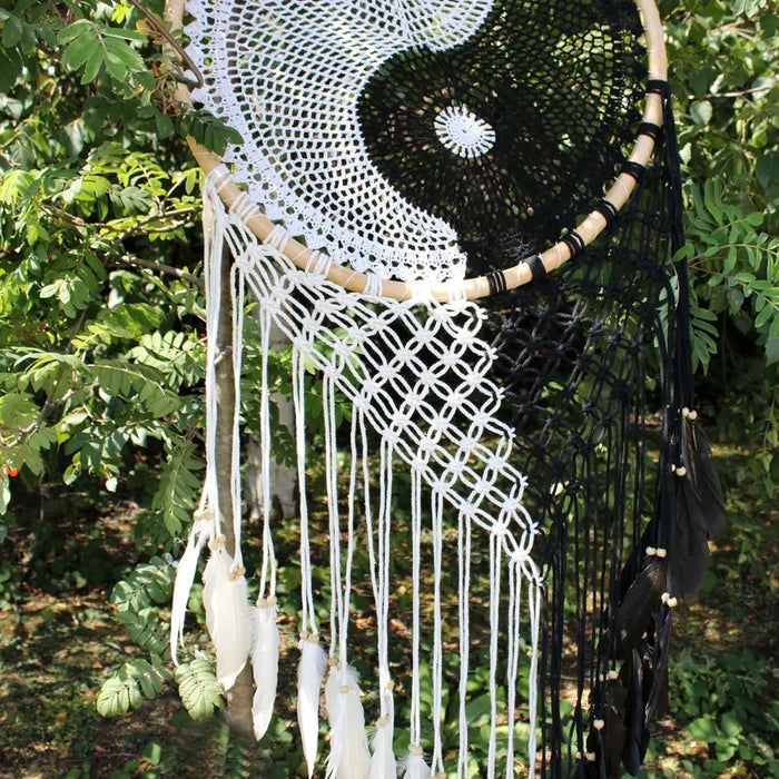 A black and white crocheted extra large bali dream catcher with yin yang design wooden beads and hanging feathers helps bad dreams