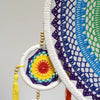 A handcrafted extra large dreamcatcher with a white macrame hoop and vivid rainbow crochet center for temple decor