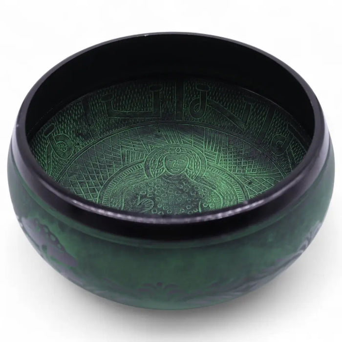 A dark green moss green mushroom singing bowl with hand engraved geometric and facial designs
