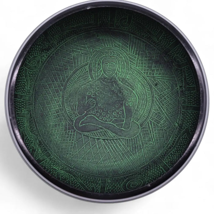 Dark green metal mushroom singing bowl with embossed seated figure and geometric patterns in moss green finish
