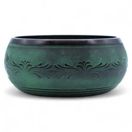 A handcrafted moss green bronze mushroom singing bowl with intricate floral etchings and a polished rim