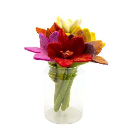 A felt flower bouquet with red purple yellow and orange petals in a clear glass jar featuring green stems